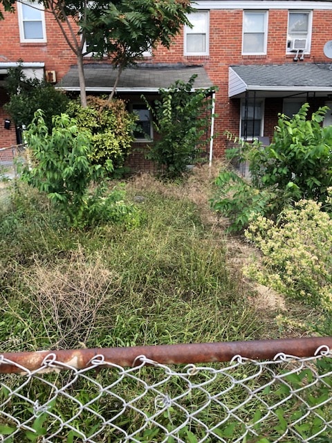 4921 Edgemere Avenue front elevation before rehabilitation — overgrown and deteriorated condition